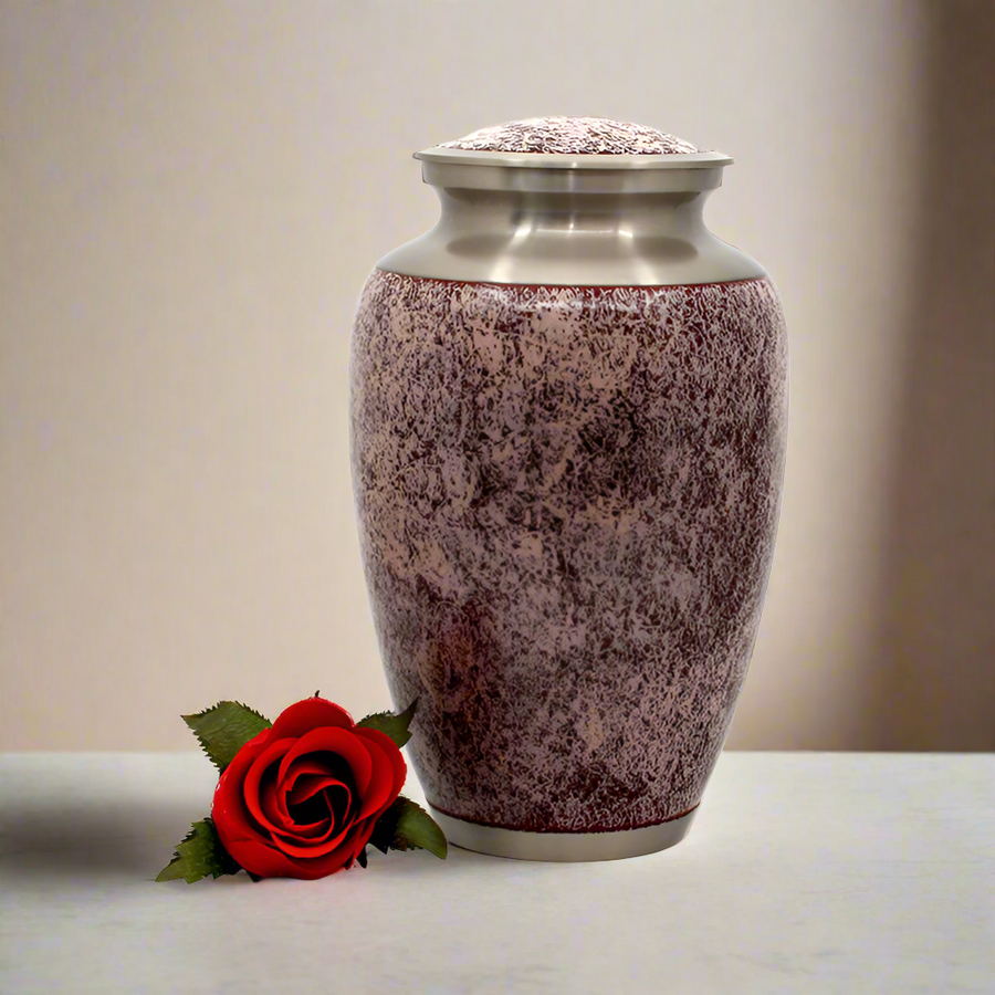 Brass metal urn with rosé finish. Placed on a granite surface