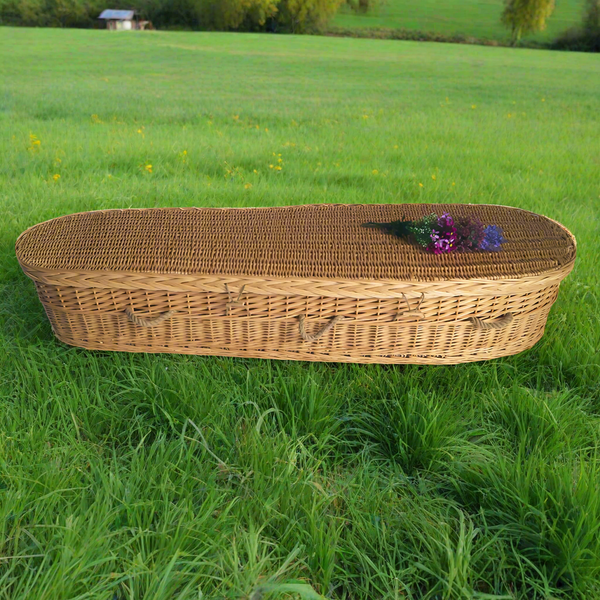 An eco friendly willow casket displayed in the field of green grass