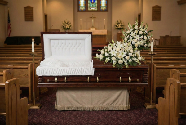Casket in a church setting with flowers and candles