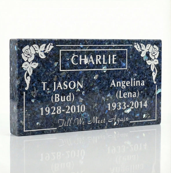 Memorial plaque with engraved names and dates on a reflective surface