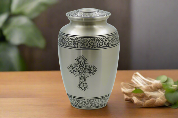 Metal urn with a cross placed on a wooden table 