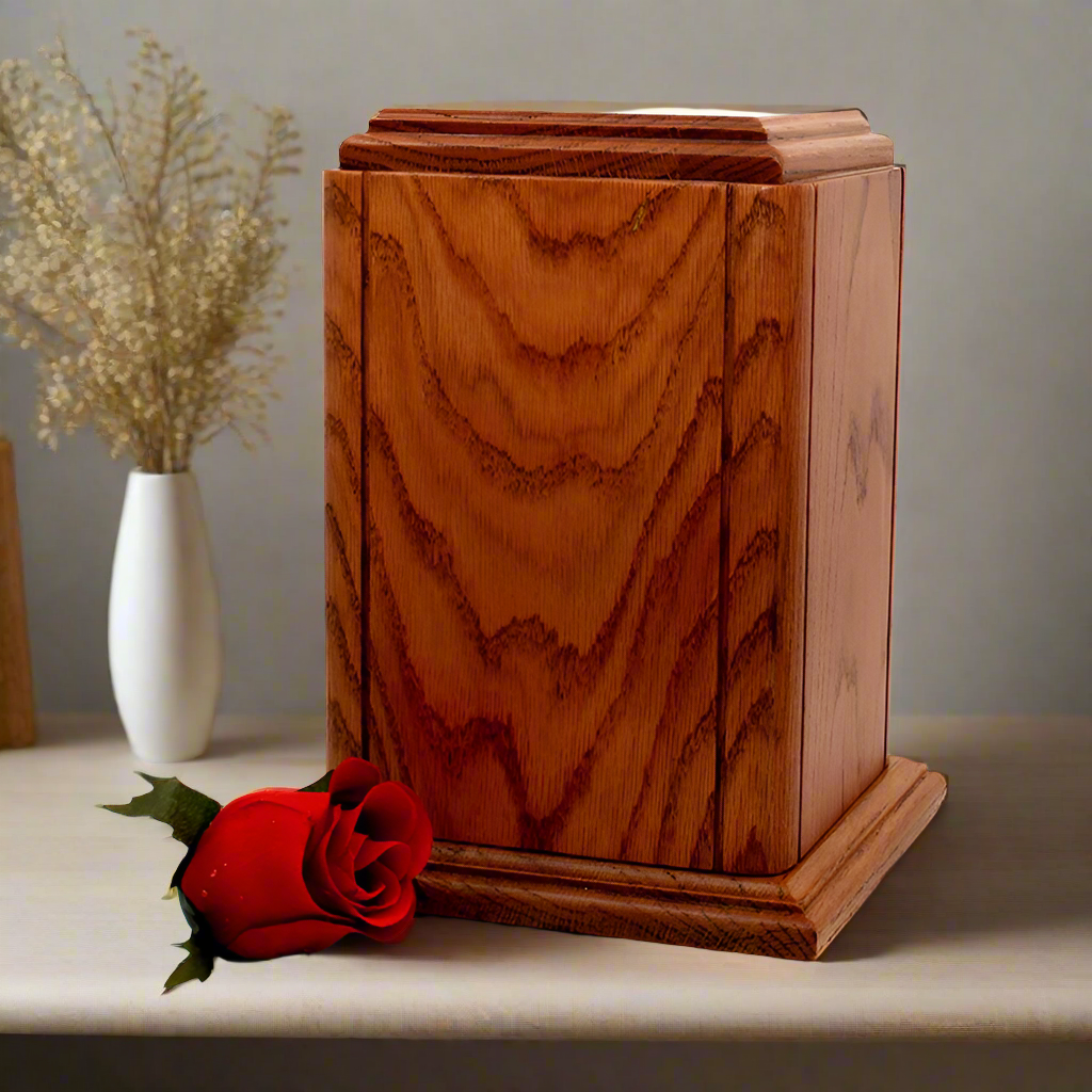 Oak urn placed on a wooden surface next to a bundle of flowers