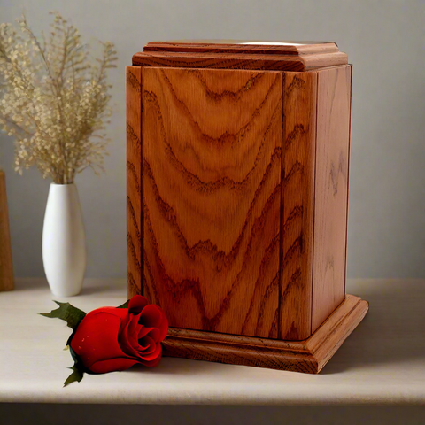 Oak urn placed on a wooden surface next to a bundle of flowers