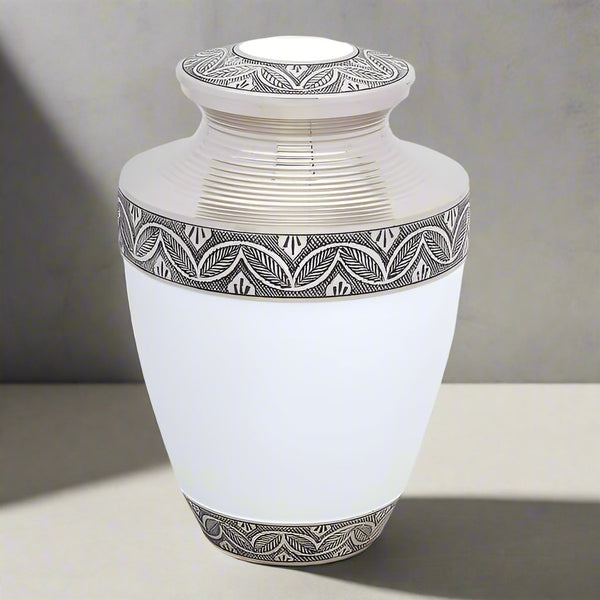 White bras metal urn with silver trim placed in a soft grey background