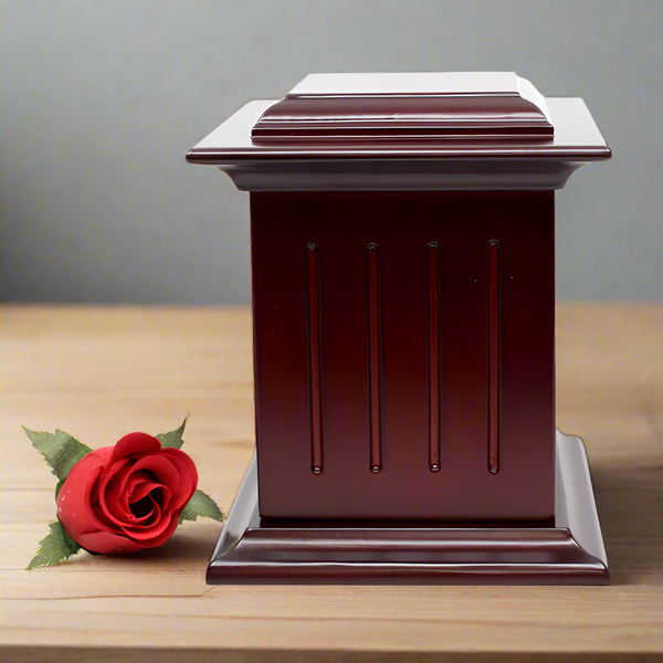 Cherry coloured wooden urn placed on a wooden surface